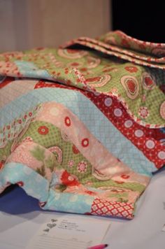 a table topped with lots of different types of quilts