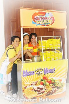 three people standing in front of a stand selling macaroni and king cheeses