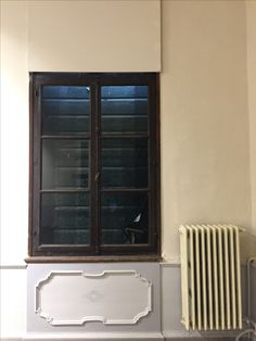 an empty room with a radiator, window and wall heater in it