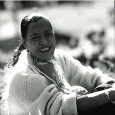 an old black and white photo of a woman smiling with her hands on her hips