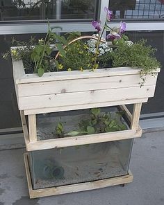 a wooden planter sitting on top of a sidewalk next to a window filled with flowers