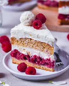 a piece of cake on a plate with raspberries and whipped cream toppings