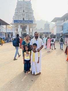 a man and two children standing in front of a temple