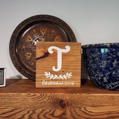 a wooden sign sitting on top of a shelf next to a blue cup and clock