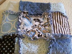 a patchwork quilt with blue and white designs on the edges, sitting on top of a bed