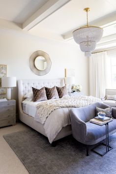 a large white bed sitting in a bedroom next to a chair and table on top of a rug