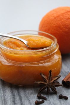 an orange jam in a glass jar with star anise and cinnamon on the side