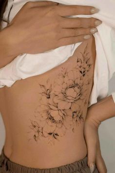 a woman's lower back tattoo with flowers on her stomach and the bottom part of her body