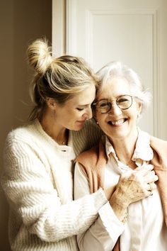 two older women embracing each other in front of a door