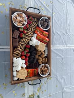 a wooden box filled with assorted snacks and desserts on top of a table