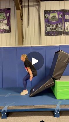 a woman standing on top of a trampoline in front of a blue wall