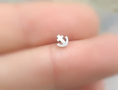 a small anchor ring sitting on top of someone's finger