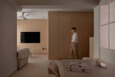 a man is walking through the living room in front of a flat screen tv on the wall