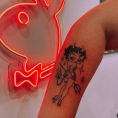 a woman with a tattoo on her arm next to a neon sign