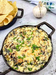 spinach dip in a cast iron skillet with tortilla chips on the side