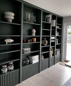 an empty room with many bookshelves and vases on the shelves in it