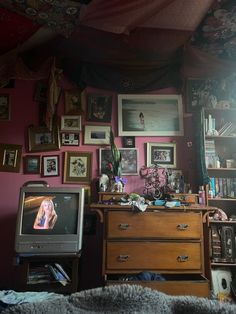 a bedroom with pink walls and lots of pictures on the wall, including a dresser