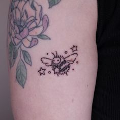 a small tattoo on the arm of a woman with flowers and a bee in it