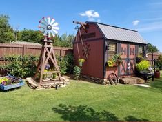 a small red shed with a windmill in the yard