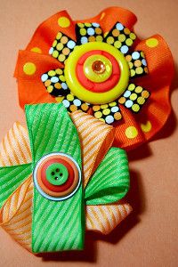 two paper flowers are sitting next to each other on a table, one is green and the other is orange