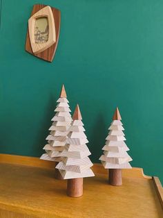 three wooden christmas trees sitting on top of a table in front of a green wall