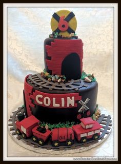 a cake made to look like a train track with the name colin on it and lots of decorations