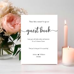 a white card with the words guest book next to a candle and flowers in a vase