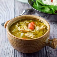 a bowl of chicken soup next to a plate of salad