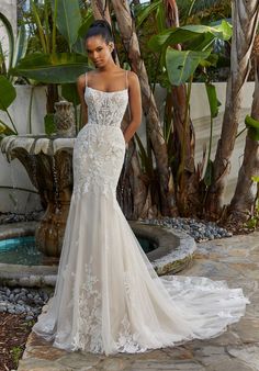 a woman in a wedding dress standing next to a fountain