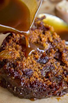 a person pouring sauce onto a piece of meat