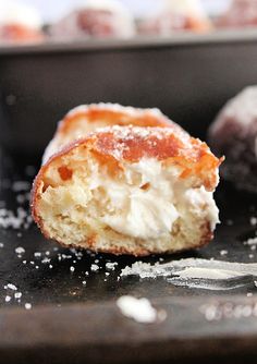 a half eaten doughnut sitting on top of a baking pan filled with powdered sugar