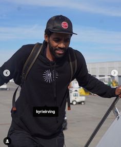 a man in a black hoodie is holding onto the side of an airplane door