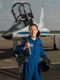 a man in blue jumpsuit standing next to an airplane