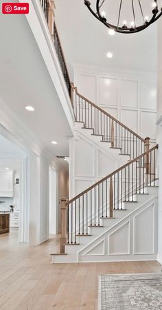 a staircase in an empty house with white walls and wood floors, along with a chandelier