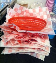 a red basket sitting on top of a pile of napkins