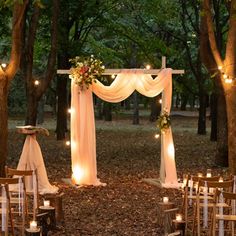 an outdoor wedding set up in the woods with candles and drapes draped over it