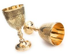 two golden goblets sitting next to each other on a white surface with one gold cup in the middle