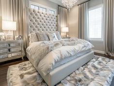 a large white bed sitting in a bedroom under a chandelier