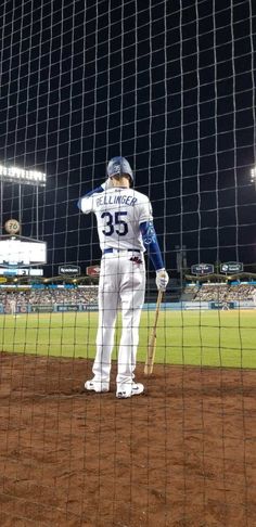 a baseball player standing on top of a field next to home plate at night with his bat in hand