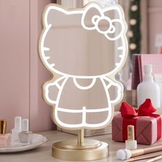 a hello kitty lighted mirror sitting on top of a table next to makeup and other items