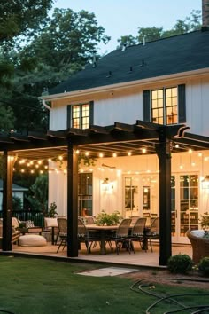 a house with lights on the front porch and covered patio in the evening time, lit up by string lights