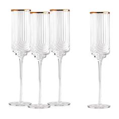 four wine glasses with gold rims are lined up