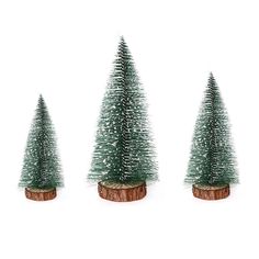 three small christmas trees sitting on top of a wooden stump in front of a white background