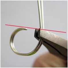 a pair of scissors being used to cut the end of a piece of metal wire