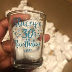 someone is holding up a glass with white marshmallows in it and blue lettering on the side