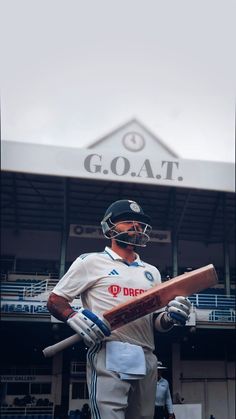 a man holding a baseball bat in front of a large building with the word goal written on it