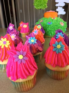 cupcakes decorated with colorful icing and flowers on top of a countertop