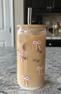 a drink in a mason jar with pink bows on the lid sitting on a counter