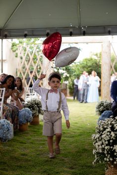 a young boy is walking down the aisle with balloons