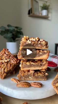 several pieces of pecan bar stacked on top of each other with nuts around them